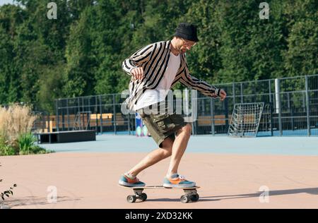 Stilvoller Erwachsener, der auf einem Skateboard in einem Skatepark fährt. Trainieren Sie Skateboarden im Freien in einem Skatepark an einem sonnigen Tag. Stockfoto