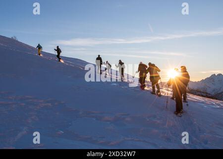 Die Gruppe der Schneeschuhe blickt auf die schneebedeckte Seite des Berges Stockfoto