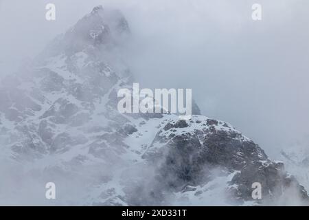 Schneebedeckte Berggipfel in Wolken Stockfoto