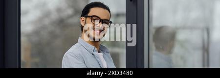 Ein fröhlicher Mann steht vor einem Fenster. Stockfoto