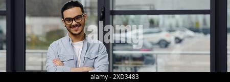 Ein Mann mit Brille steht kontemplativ vor einem Fenster. Stockfoto