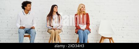 Gruppe stilvoller Einzelpersonen, die auf Stühlen vor einer leeren Wand sitzen. Stockfoto