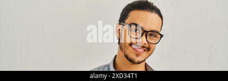 Ein Mann mit Brille, der vor weißem Hintergrund lächelt. Stockfoto