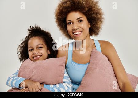 Glückliche afroamerikanische Mutter und Tochter im Pyjama posieren auf grauem Hintergrund. Stockfoto