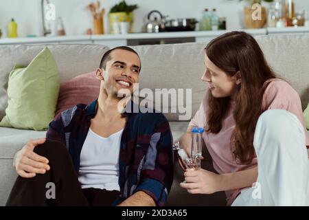 Paare in lässiger Kleidung genießen einen friedlichen Moment zusammen auf einer gemütlichen Couch zu Hause und halten eine Glasbong Stockfoto