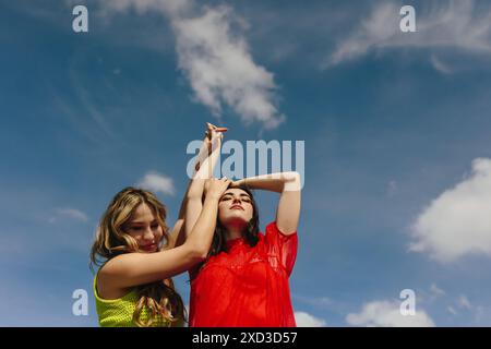 Zwei junge Frauen treiben spielerische Aktivitäten unter einem leuchtend blauen Himmel an, was ein Thema der Freundschaft und Freizeit in einer Outdoor-Umgebung andeutet Stockfoto