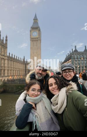 Eine vierköpfige Familie, darunter ein Mann, zwei junge Frauen und ein Mädchen im Teenageralter, lächelt vor dem historischen Big Ben in London und zeigt eine schöne Schönheit Stockfoto