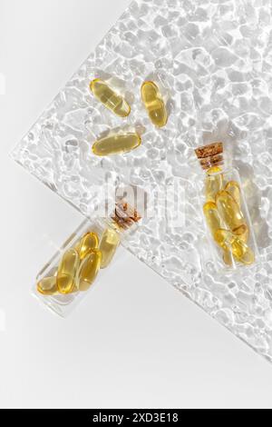 Omega 3 Kapseln auf einer strukturierten Glasplatte mit lichtreflektierenden Mustern, die den goldenen Farbton und die transparente Schale der Pillen hervorheben, EM Stockfoto