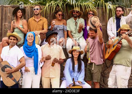 Eine multirassische Gruppe von Freunden versammelt sich zu einer Party im Freien, um Lachen und Musik zu teilen. Männer und Frauen verschiedener Ethnien, einschließlich Kaukasier, AF Stockfoto