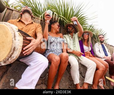 Von unten versammelt sich eine Gruppe von Freunden zu einer Party im Freien, um Lachen und Musik zu teilen. Männer und Frauen verschiedener Ethnien, einschließlich Cauc Stockfoto