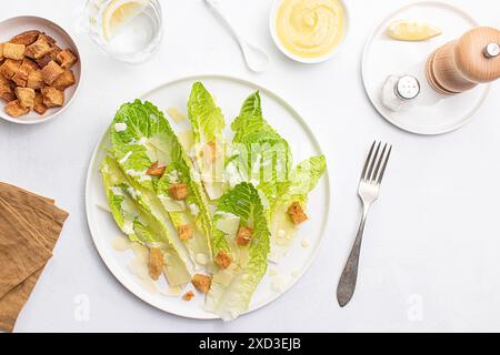 Blick von oben auf einen Caesar-Salat mit knusprigem Römersalat, Croutons und rasiertem Parmesan, elegant auf weißem Hintergrund überzogen. Stockfoto