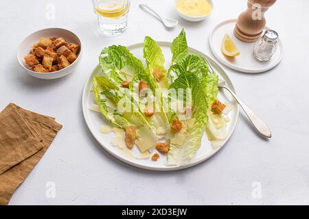 Blick von oben auf einen klassischen Caesar-Salat mit knusprigem Romaine-Salat, knusprigen Croutons, geschliffenem Parmesankäse und cremigem Dressing, serviert auf einem weißen Teller Stockfoto