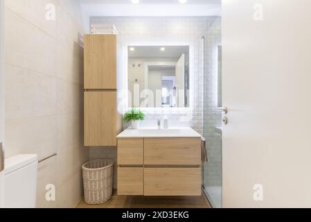 Dieses Bild zeigt ein modernes Badezimmer mit Holzwaschtisch, hellen Fliesen und minimalistischem Design. Hell und luftig, inklusive Stockfoto