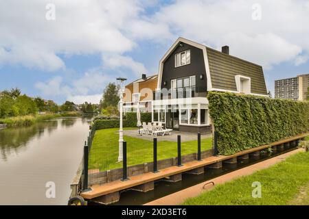 Wunderschönes Haus am Kanal mit gepflegtem Rasen und gemütlicher Terrasse. Die moderne Architektur und die ruhige Umgebung bieten eine perfekte Mischung aus Ihnen Stockfoto