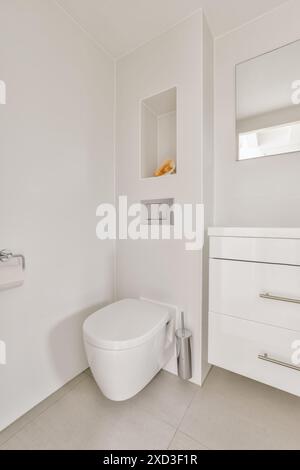 Ein stilvolles, minimalistisches Badezimmer in sauberem weiß mit modernen Armaturen, eingebauten Regalen und Tageslicht in der Stuyvesantstraat, Amsterdam Stockfoto