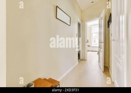 Dieses Bild zeigt einen hellen und ruhigen Flur mit minimalistischem Dekor mit einer warmen Holzkonsole und gerahmter Wandkunst. Die sauberen, weißen Wände c Stockfoto