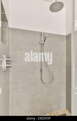 Ein modernes Badezimmer mit Duschkabine mit Regendusche und abnehmbarem Duschkopf, graue Fliesen, verleihen jedem Innenraum eine elegante Note Stockfoto