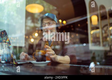 Ein erfahrener männlicher Profi arbeitet in einem Café an seinem Laptop und nimmt bei einer Tasse Kaffee den modernen, ferngesteuerten Lebensstil wahr Stockfoto