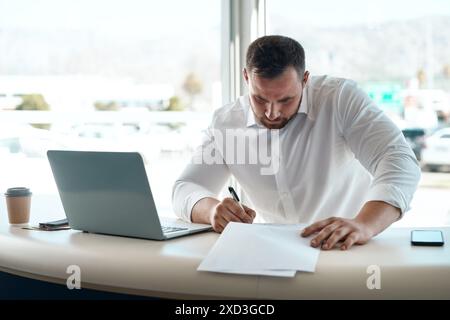 Mann, Vertrag und Schreiben im Büro bei Autohändler mit Deal, Verkauf oder Rabatt für Fahrzeug. Person, Autoverkäufer und Dokumentation für Finanzen Stockfoto