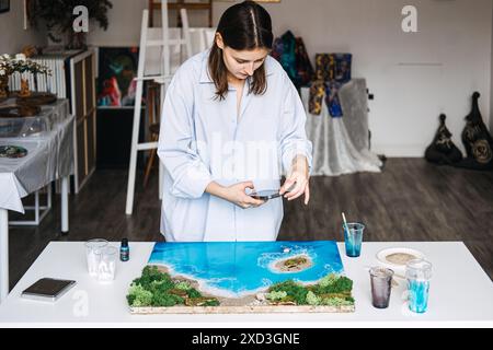 Eine Künstlerin, die in ihrem Studio eine Epoxidharzlandschaft herstellt Stockfoto