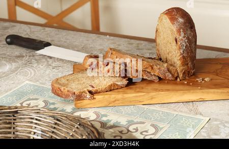 Hausgemachtes Roggenbrot mit Preiselbeeren auf Holzbrett. Innenraum der Küche. Ernährung und Gesundheit. Stockfoto