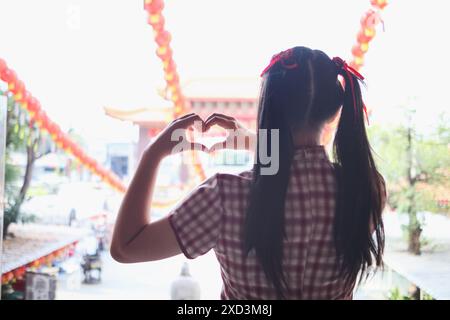 Eine junge Frau hebt ihre Hände, um ein Herzsymbol zu machen, das Liebe und Freundschaft bedeutet. Das Konzept von ​​using Händen zur Herstellung eines Herzsymbols stellt den Mittelwert dar Stockfoto