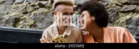 Vielfältige, schöne Lesben bei einem Date in einem gemütlichen Café, sitzen eng zusammen. Stockfoto