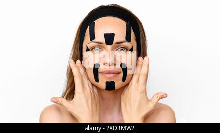 Weibliches Schönheitsmodell, das kinesio-Klebebänder auf ihr Gesicht aufträgt. Schönheit, Körper- und Hautpflege. Stockfoto