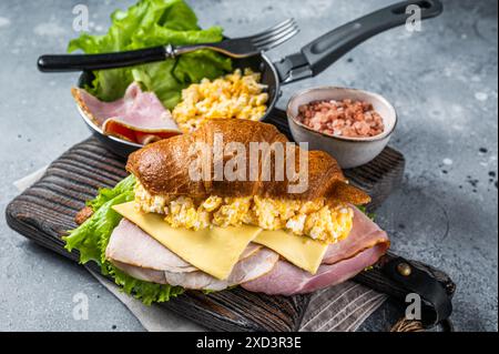 Croissant Sandwich mit truthahnschinken, Rührei, Käse und Salat. Grauer Hintergrund. Draufsicht. Stockfoto