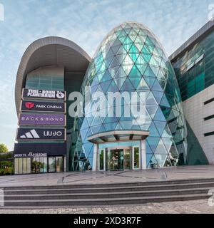 Baku, Aserbaidschan - 10. Mai 2024: Nur wenige Menschen laufen in der Nähe des modernen Designs der Park Bulvar Mall, an einem sonnigen Tag mit klarem blauem Himmel über dem Himmel Stockfoto