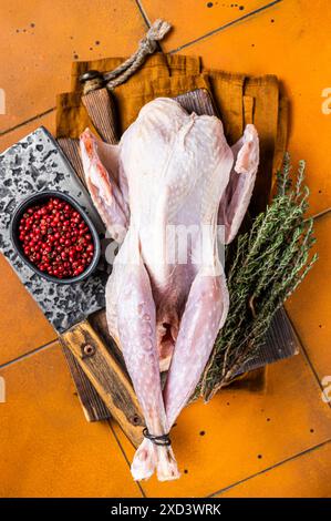 Farm Rohe Guineafowl, Perlhühner mit Kräutern zum Kochen. Orangefarbener Hintergrund. Draufsicht. Stockfoto