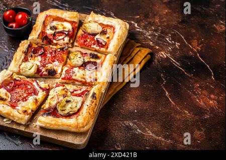 Vegetarische Blätterteigpizza mit Artischocke, Mozzarella, Tomaten und Käse auf einem Holzbrett. Dunkler Hintergrund. Draufsicht. Kopierbereich. Stockfoto