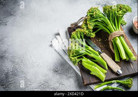 Frische Broccolini-Sprossen auf dem Schneidebrett bereit zum Kochen. Weißer Hintergrund. Draufsicht. Kopierbereich. Stockfoto