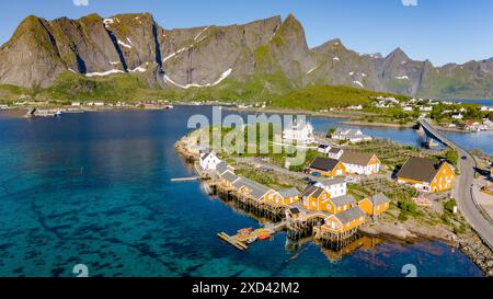 Sakrisoy, Lofoten, Norwegen ein kleines Dorf in Lofoten, Norwegen, mit bunten Häusern und einer Brücke, die zwei Inseln verbindet. Das klare blaue Wasser und die atemberaubende Bergkulisse schaffen eine malerische Kulisse. Stockfoto