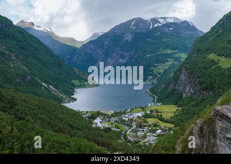 Ein Panoramablick auf einen malerischen norwegischen Fjord, mit majestätischen Bergen, üppigem Grün, einem sich windenden Fluss und einem kleinen Dorf am Fuße der Berge. Geiranger Fjord Norwegen Stockfoto