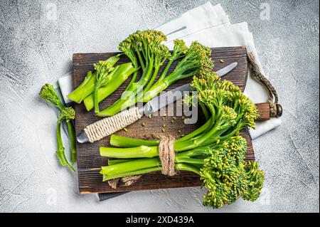 Frischer Broccolini-Sprossen auf dem Schneidebrett, bereit zum Kochen. Weißer Hintergrund. Draufsicht. Stockfoto