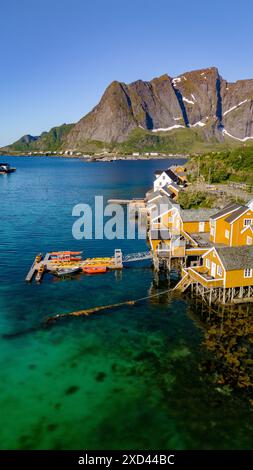 Ein Blick aus der Vogelperspektive auf ein malerisches norwegisches Dorf an der Küste von Lofoten, mit einer Reihe von bunten Häusern auf Stelzen mit Blick auf das kristallklare Wasser. Sakrisoy, Lofoten, Norwegen Stockfoto