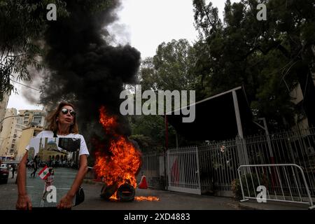 Beirut, Libanon. 20. Juni 2024, Beirut, Beirut, Libanon: Eine Verwandte der dreijährigen libanesischen Alexandra Najjar, die bei der massiven Explosion des Hafens am 5. August 2020 ihr Leben verlor, trägt ihr Bild vor brennenden Reifen im Justizpalast von BeirutÃ¢â‚¬â„¢während eines Protestes von Familien von Opfern der Explosion. Weniger als zwei Monate bis zum 4. Jahrestag der Explosion, bei der mehr als 200 Menschen ums Leben kamen, ist fast alles unbekannt Ã¢â‚¬ von der Person, die die Verbringung angeordnet hat, bis hin zu den wiederholten Warnungen der Beamten vor der Gefahr. Quelle: ZUMA Press, Inc./Alamy Live News Stockfoto