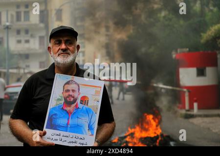 Beirut, Libanon. 20. Juni 2024, Beirut, Beirut, Libanon: Vater von Ahmad al-Kaadan, wer bei der massiven Explosion des Hafens Beirut am 5. August 2020 ums Leben kam, trägt sein Bild mit dem Slogan: Ã¢â‚¬Â Gerechtigkeit für Ahmad al-Kaadan, Märtyrer des Hafens Beirut blastÃ¢â‚¬Â, steht vor brennenden Reifen im Justizpalast von BeirutÃ¢â‚¬â„¢während eines Protests von Familien von Opfern. Quelle: ZUMA Press, Inc./Alamy Live News Stockfoto