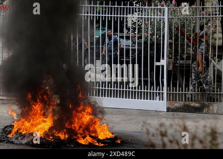 Beirut, Libanon. 20. Juni 2024, Beirut, Beirut, Libanon: Libanesische Polizisten, die den Eingang des Justizpalastes von BeirutÃ¢â‚¬â„¢sichern, werden hinter brennenden Reifen gesehen, die von Opfern von Familien des massiven Beiruts vom 5. August 2020 gesetzt wurden. Weniger als zwei Monate bis zum 4. Jahrestag der Explosion, bei der mehr als 200 Menschen ums Leben kamen, ist fast alles unbekannt Ã¢â‚¬ von der Person, die die Verbringung angeordnet hat, bis hin zu den wiederholten Warnungen der Beamten vor der Gefahr. Die Familien der Opfer haben auf Antworten gedrängt und politischen Parteien vorgeworfen, die lokalen Ermittlungen zu behindern. Quelle: ZUMA Press, Inc./Alamy Stockfoto