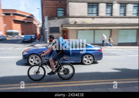 Ein Radfahrer mit Bart und Sonnenbrille fährt an einem warmen Sommertag mit einem Kurierrad durch das Zentrum von Leeds Stockfoto