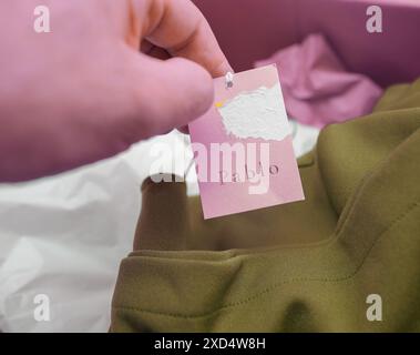 Paris, Frankreich - 28. März 2024: Eine männliche Hand, die das neue Pablo Fashion Clothing Tag mit dem Logo vor einem Hintergrund aus Kleid und Karton hält, was das schnelle Fashion Branding unterstreicht Stockfoto