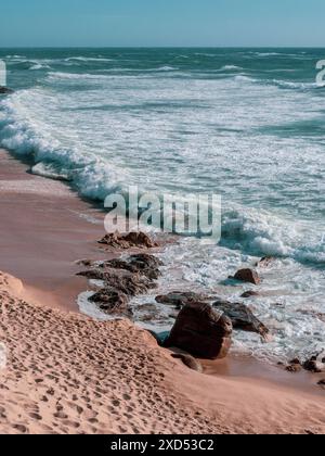 Sehen Sie, wie die Wellen des Atlantischen Ozeans auf dem großen felsigen Stein am wunderschönen Vulkanstrand portugals brechen Stockfoto