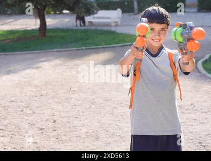 Junge vor Teenager mit Wasserpistolen im Park Stockfoto