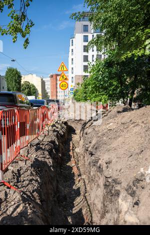 Graben für die Verlegung von elektrischen Kabeln in Stadtstraßen, Versorgungsarbeiten für den Austausch von Rohrleitungen. Stockfoto