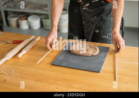 Nahaufnahme von Töpferhänden, die Ton ausrollen. Stockfoto