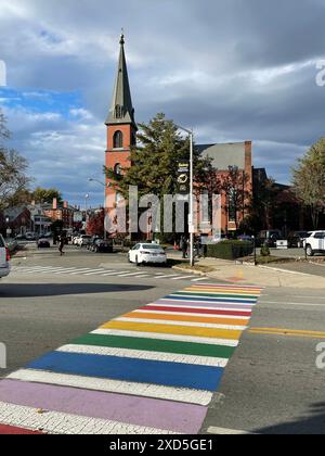 Die Farben eines Regenbogens, der die LBGT-Pride-Flagge repräsentiert, sind in den Linien eines Straßenübergangs vor einer Kirche in Salem Massachusetts gemalt Stockfoto