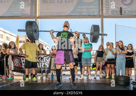 Athleten, die Gewichtheben bei einem intensiven CrossFit-Wettkampf in Sevilla, Spanien, durchführen. Die Massen beobachten die Teilnehmer und feuern sie an. Stockfoto