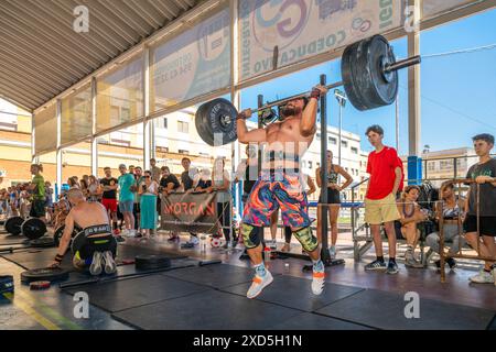 Athleten, die Gewichtheben bei einem intensiven CrossFit-Wettkampf in Sevilla, Spanien, durchführen. Die Massen beobachten die Teilnehmer und feuern sie an. Stockfoto