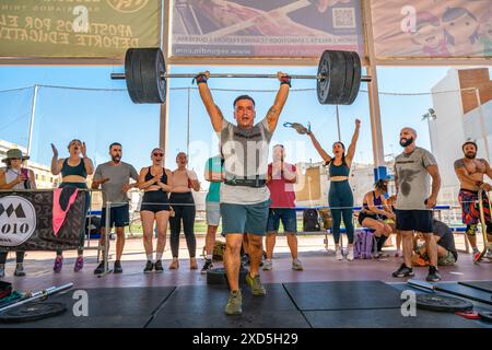 Athleten, die Gewichtheben bei einem intensiven CrossFit-Wettkampf in Sevilla, Spanien, durchführen. Die Massen beobachten die Teilnehmer und feuern sie an. Stockfoto